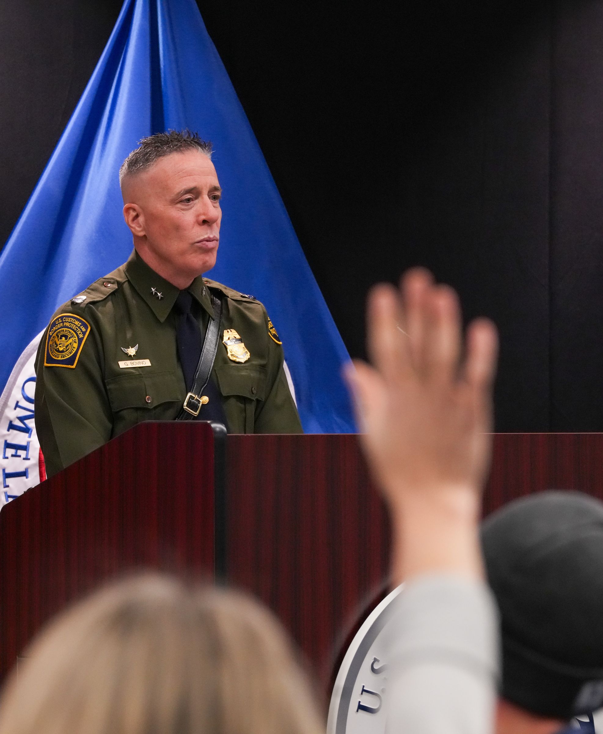 Gregory K. Bovino speaking from a podium during a public briefing
